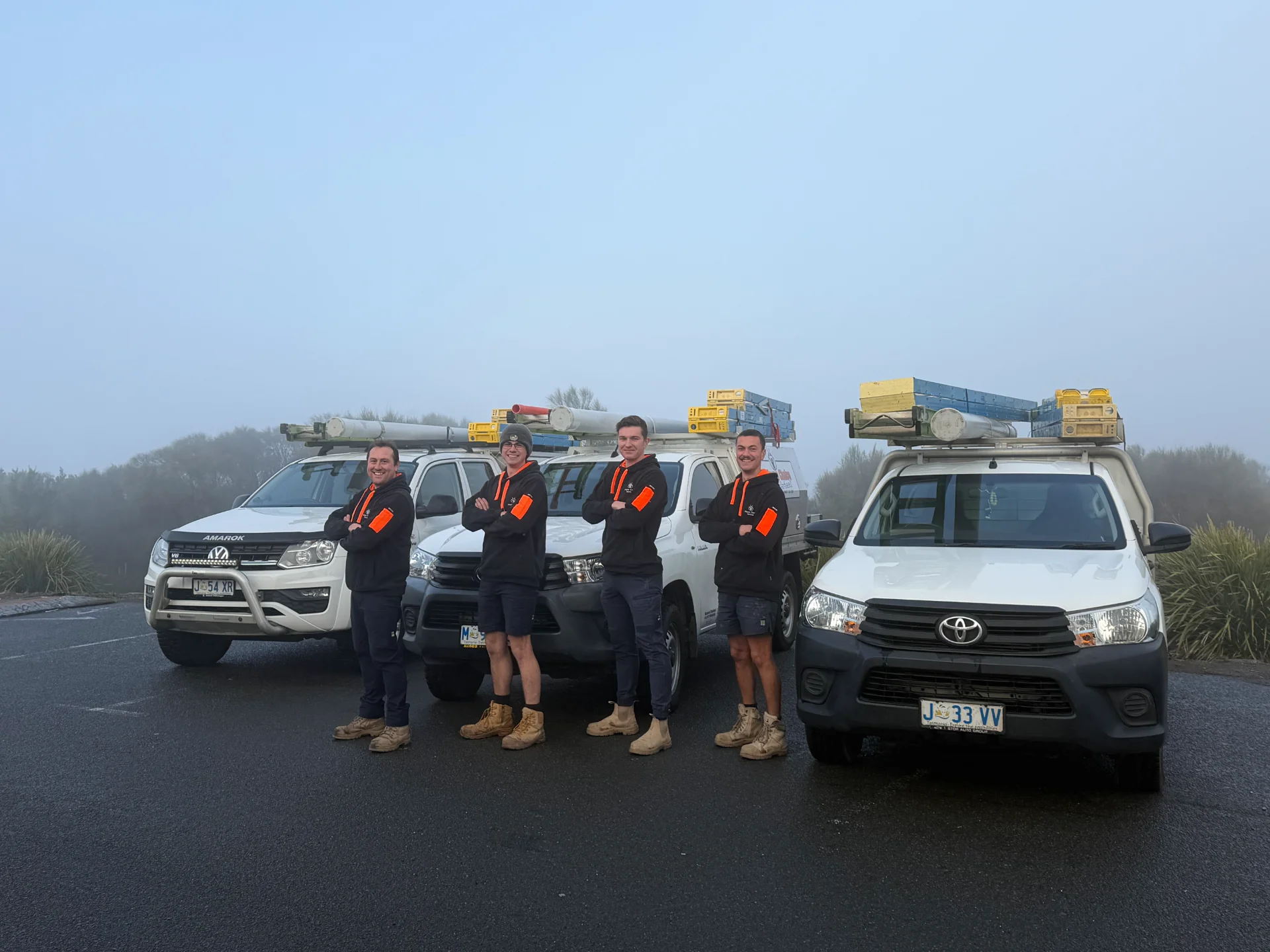 Mayne Choice Electrical team standing with their service utes on a foggy Southern Tasmania morning